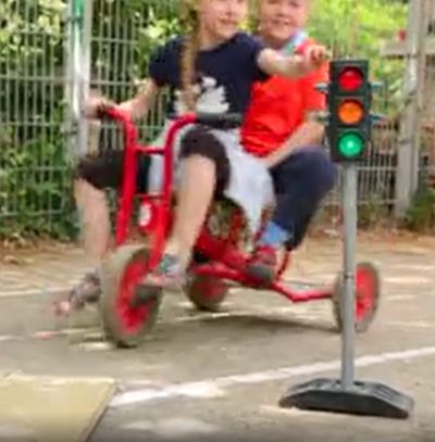 Picture shows children on tricycle and traffic light